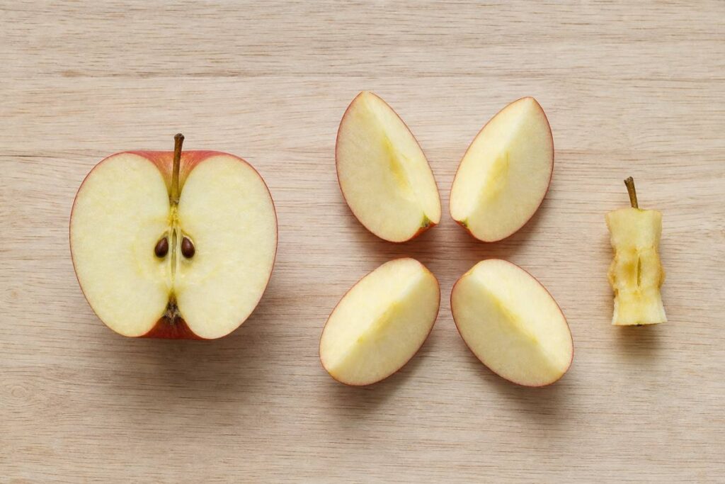 Apple cut through the core showing seeds beside an apple cut into wedges around the core with the seeds removed