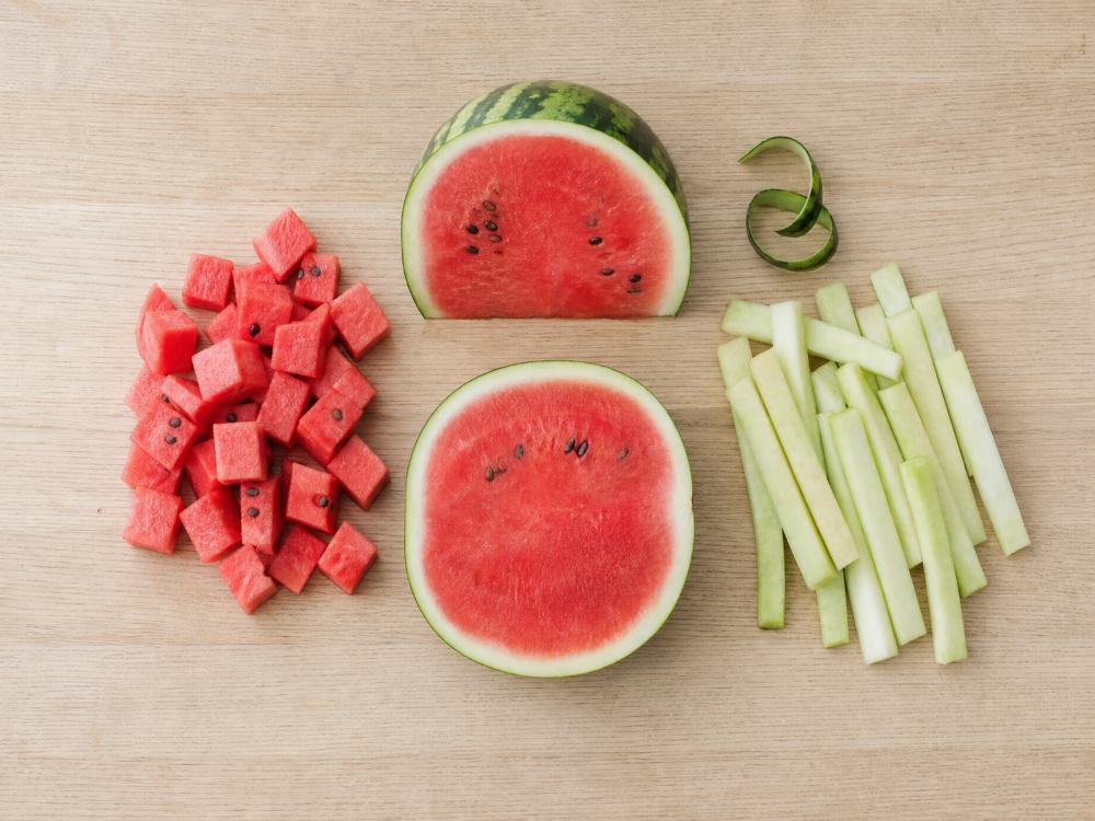 Pale inner watermelon rind cut into strips beside cubes of red flesh with seeds